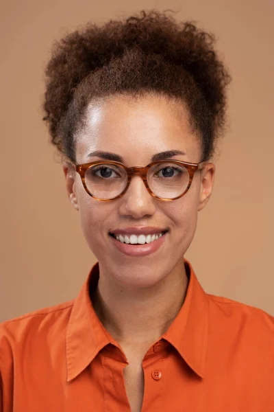 Pionowy Portret Uśmiechniętej Afroamerykanki Okularach Uśmiechniętej Kamery Odizolowanej Brązowym Tle — Zdjęcie stockowe