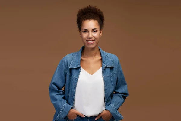 Portrait of smiling confident African American business woman looking at camera isolated on brown background. Successful business concept