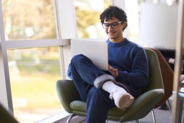 Yakışıklı, kendine güvenen genç İspanyol erkek serbest girişimci girişimci projesi, iş ortaklarıyla çevrimiçi iletişim kurma, modern, rahat bir ofisin bilgisayarında uzaktan çalışma.