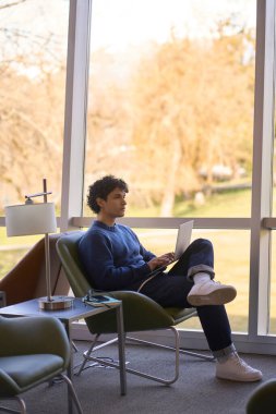 Düşünceli genç işadamı, dizüstü bilgisayar kullanıyor, yeni bir iş projesi üzerinde çalışıyor, iş arkadaşları ve ortaklarla toplantılar planlıyor, modern ofis içi ile iletişim kuruyor. Çevrimiçi İş Başlatan İnsanlar