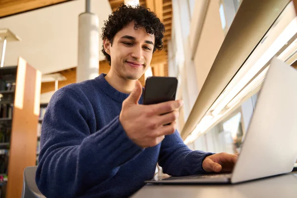 Mladý Student Latinské Ameriky Usmívá Při Kontrole Mobilního Telefonu Sedí — Stock fotografie