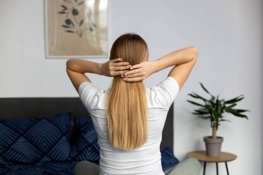 Uzun, sağlıklı saçları olan, duştan sonra saçlarının kalitesinin tadını çıkaran çekici bir kadın. Genç bayan kahverengi saçlarına dokunuyor ve evde dinleniyor. Güzellik konsepti