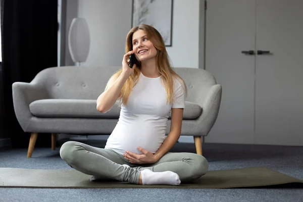 Vacker Leende Gravid Kvinna Håller Magen Talar Mobiltelefon Sitter Lotus — Stockfoto