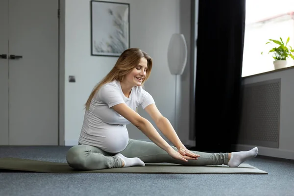 Leende Gravid Kvinna Stretchar Gör Övningar Sittande Golvet Hemma Graviditet — Stockfoto