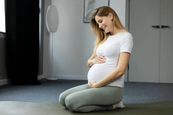 Leende Gravid Kvinna Som Håller Sin Mage Sittande Golvet Hemma — Stockfoto
