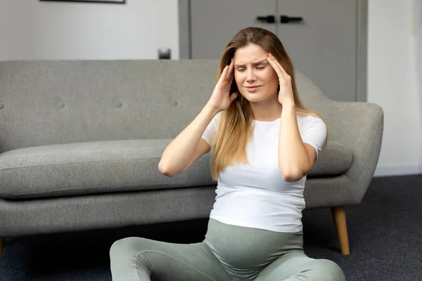 頭痛や片頭痛に苦しむ悲しい妊婦は 病気を感じ 家に座っています — ストック写真