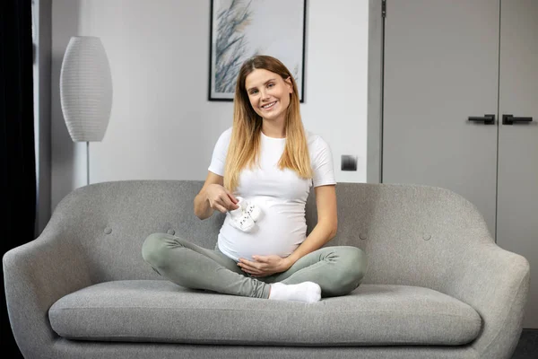 Ung Leende Gravid Kvinna Tittar Små Skor För Det Ofödda — Stockfoto
