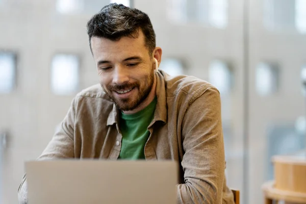 Gülümseyen Adamının Ofiste Otururken Bilgisayarını Kullanması Kablosuz Kulaklıklı Spanyol Adam — Stok fotoğraf