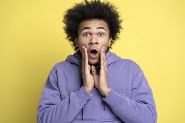 Sarı arka planda izole edilmiş, ağzı açık el ele tutuşan genç adamın portresi. Sopping, satış konsepti 