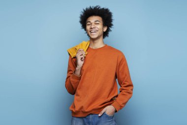 Closeup portrait of smiling African American man wearing stylish clothes isolated on blue background, copy space. Happy smart student with curly hair looking at camera posing for pictures, studio shot 