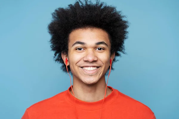 魅力的な笑顔の本物の肖像画カラフルな背景に隔離されたカメラを見て赤いイヤホンで音楽を聞いてアフリカ系アメリカ人男性 人と感情の概念 — ストック写真
