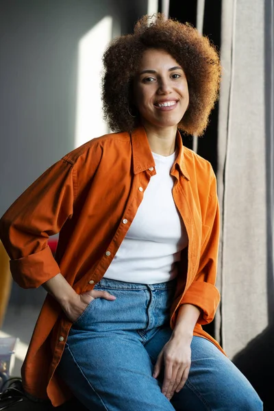 Autentyczny Portret Pięknej Uśmiechniętej Afroamerykanki Stylowej Pomarańczowej Koszulce Dżinsach Siedzących — Zdjęcie stockowe