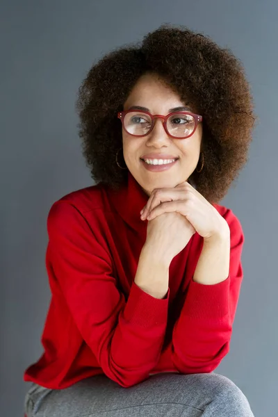 一个漂亮的微笑的女人的画像 穿着红色高领毛衣和时髦的红色眼镜 背景是灰色的 聪明的苦思冥想的学生 — 图库照片