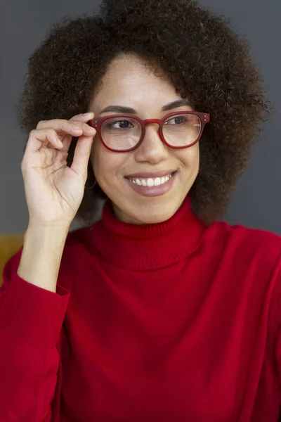穿着时髦的红色眼镜和红色高领毛衣的非洲裔美国女人面带微笑 看上去与背景格格不入 视觉概念 — 图库照片