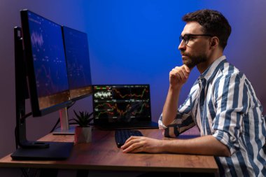 Bilgisayar monitörüne bakan ciddi bir kripto tüccarı, kripto grafiğiyle çevrimiçi çalışıyor modern ofiste oturuyor, pazarı araştırıyor ve analiz ediyor. Başarılı iş, çevrimiçi ticaret kavramı