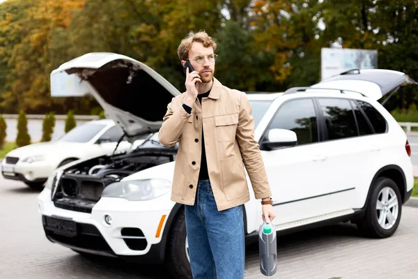 매력적 남자가 자동차 근처에 후드를 스마트폰으로 이야기하고 있습니다 자동차 서비스 — 스톡 사진