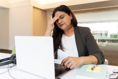 Mutsuz Hintli iş kadınının dizüstü bilgisayarla başı ağrıyormuş, ofis projesinde çalışıyormuş. Başarısız iş. Çok çalışan ve stresli serbest çalışan beyin fırtınası, son teslim tarihini kaçıran iş yerinde oturan