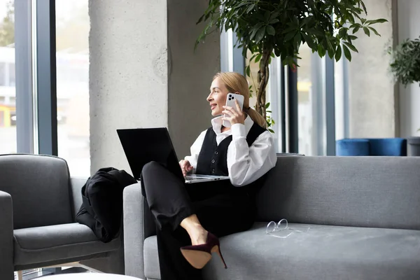 Poważna Bizneswoman Siedzi Kanapie Rozmawia Przez Smartfona Nowoczesnej Przestrzeni Biurowej — Zdjęcie stockowe
