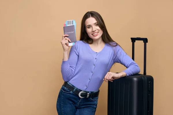 一位身穿休闲装的游客 头戴手提箱和登机牌 被米色背景隔离 情绪愉悦 等待着即将到来的航班 — 图库照片