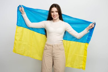 Ukrayna bayrağı taşıyan genç ve güzel bir kadın, beyaz arka planda izole edilmiş bir kutlama günü.