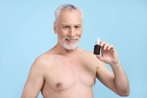 Beyaz Saçlı Yakışıklı Yaşlı Adam Yaşlanmayı Önleyici Serumla Kavanoz Gösteriyor — Stok fotoğraf