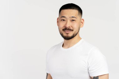 Beyaz arka planda izole edilmiş kameraya bakan gülümseyen Asyalı adam. Yakışıklı genç adam bir resim için poz veriyor, fotokopi alanı, reklam