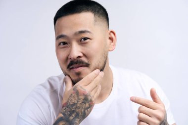 Genç Koreli adamın nemlendirici yüz kırışıklık önleyici krem sürmesine yakın çekim. Milenyum erkeği sağlıklı yumuşak cilt için besleyici yüz serumu ya da losyonu kullanır. Cilt bakımı, güzellik konsepti 