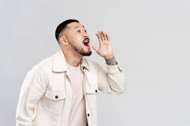 Duygusal Asyalı bir adam el ele tutuşuyor, satıştan bahsedip bağırıyor, gri arka planda tek başına bakıyor. Promosyon, alışveriş konsepti