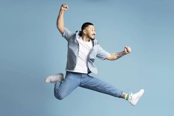 スタイリッシュなカジュアルな服を着ているアジア人男性 速く走る白い靴 ブルーで孤立した高いジャンプ — ストック写真