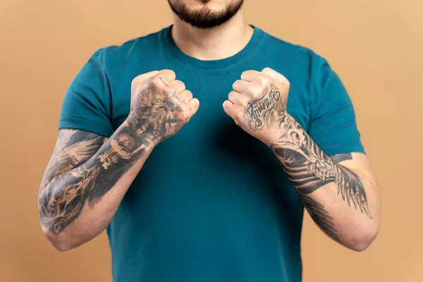 ベージュの背景に隔離された緑色のカジュアルなTシャツを着て腕にスタイリッシュなタトゥーを示す筋肉質のアジア人の男性のクロップされた肖像画 モックアップ — ストック写真