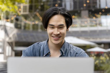 Laptop kullanan başarılı Asyalı adam portresi, açık havada çalışan kendine güvenen Japon serbest yazar. Modern teknoloji kavramı