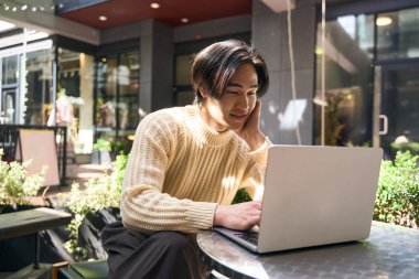 Kafe işyerinde bilgisayar ekranı okuyan başarılı bir Japon yazar. Kendine güvenen Asyalı yazar dışarıda dizüstü bilgisayar kullanıyor. Teknoloji konsepti 