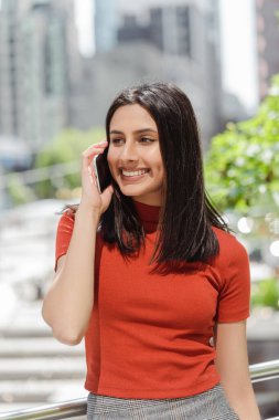 Cep telefonuyla konuşan güzel Hintli bir kadının özgün portresi. Şehir sokağında dikilirken telefona bakmak, kopyalama alanı. Teknoloji konsepti 