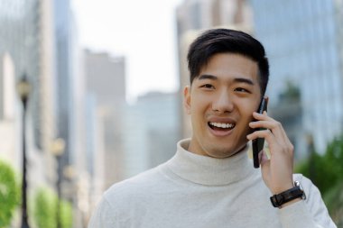 Mutlu Asyalı yakışıklı işadamı cep telefonuyla konuşuyor. Caddeye bakıyor, fotokopi çekiyor. Başarılı iş, teknoloji kavramı