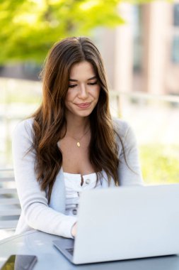 İnternette dizüstü bilgisayar kullanan, iş yerinde oturmayı planlayan güzel gülümseyen bir kadının portresi. Akıllı öğrenim, eğitim, teknoloji sektörü konsepti