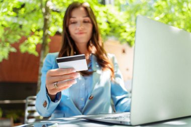 Çekici bir kadın, elinde dizüstü bilgisayarla kredi kartı tutan girişimci, iş yerinde online alışveriş yapan, seçici bir odak noktası olan. Serbest çalışan ödeme alır. Başarılı iş, elektronik para