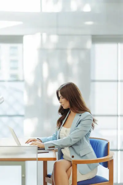 Confident woman professional designer using laptop, working online looking at screen in modern office. Freelancer copywriter typing sitting at workplace. Attractive student studying online