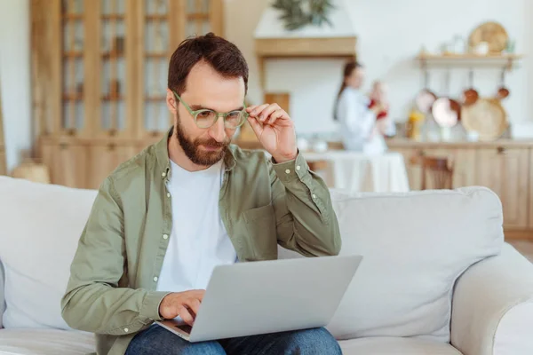 Focused bearded man, freelancer wearing stylish eyeglasses using laptop computer working online from home. Technology, remote job concept