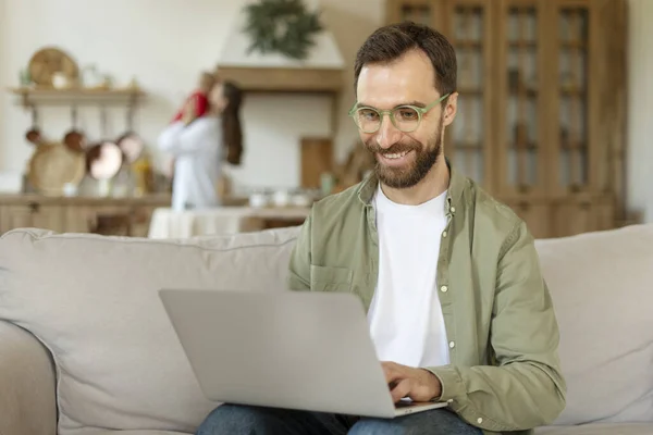Gülümseyen sakallı adamın portresi, evden çalışan dizüstü bilgisayarla gözlük takan serbest çalışan biri. Teknoloji, uzak iş kavramı 