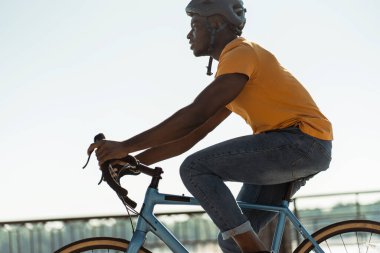 Kentsel yaz caddesinde kask takan yakışıklı, gülümseyen Afrikalı Amerikalı adam. Spor, hobi, aktif yaşam tarzı konsepti 