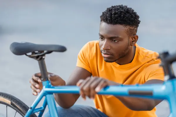 Portret Atrakcyjnego Nigeryjczyka Sprawdzającego Siedzenie Rowerowe Ulicy Młody Poważny Mężczyzna — Zdjęcie stockowe