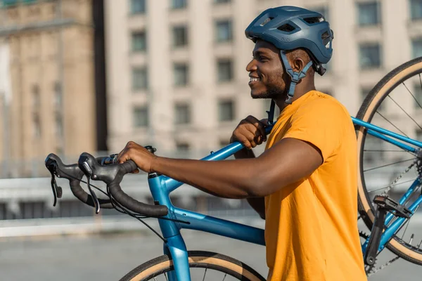 Portret Przystojnego Uśmiechniętego Afroamerykanina Kasku Trzymającego Rower Chodzącego Ulicą Miejską — Zdjęcie stockowe