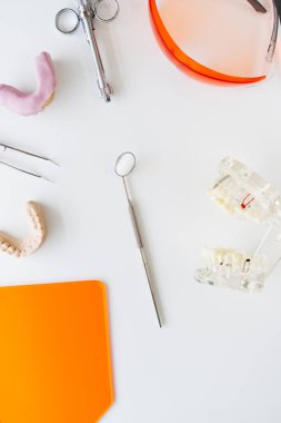 Diş aynasının üst görüntüsü, masada duran demir kıskaç ve diş modelleri. Diş aygıtlarının dikey resmi