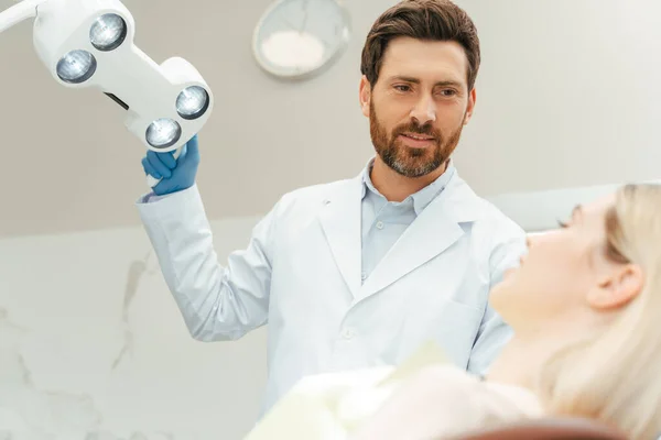 Professional Bearded Dentist Turning Lamp While Preparing Checking Woman Teeth — Stock Photo, Image