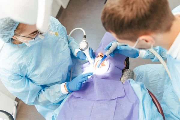 Cropped view of the surgeon and nurse during dental operation. Anesthetized patient in the operating room. Installation of dental implants or tooth extraction in clinic