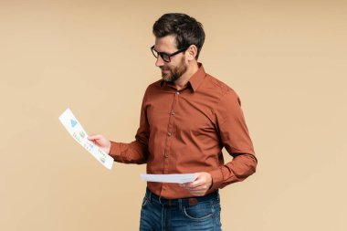 Yakışıklı, gülümseyen orta yaşlı iş adamı portresi, gözlüklü menajer elinde belgeler, bej arka planda izole edilmiş kitap sözleşmesi. Başarılı iş konsepti 