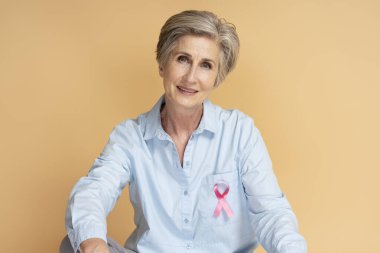 Stüdyoda pembe kurdeleli gülümseyen son sınıf öğrencisi. Sağlık hizmetleri. Göğüs kanseri farkındalığı ayı