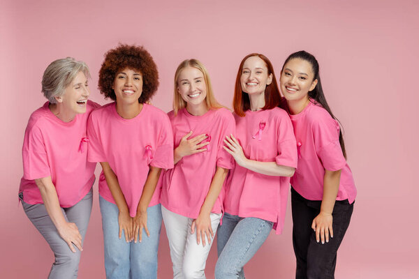 Group of women with pink ribbon communication isolated on pink background. Breast cancer awareness