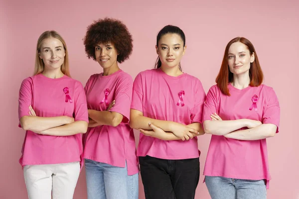Women holding arm crosseD wearing t shirts with pink ribbon . Breast cancer awareness month concept