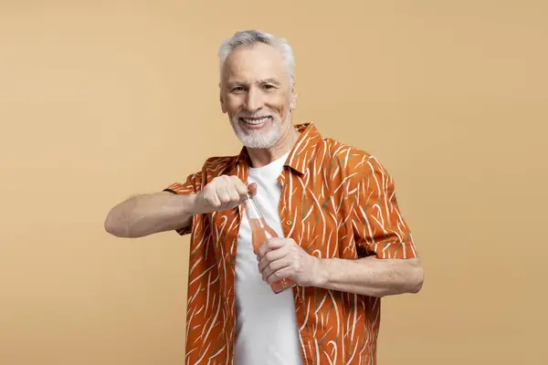 面带微笑的60岁男子穿着时髦的橙色衬衫和白色T恤 打开柠檬水 看着被米色背景隔离的相机 暑假概念 — 图库照片